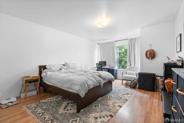 a spacious bedroom with a bed and wooden floor