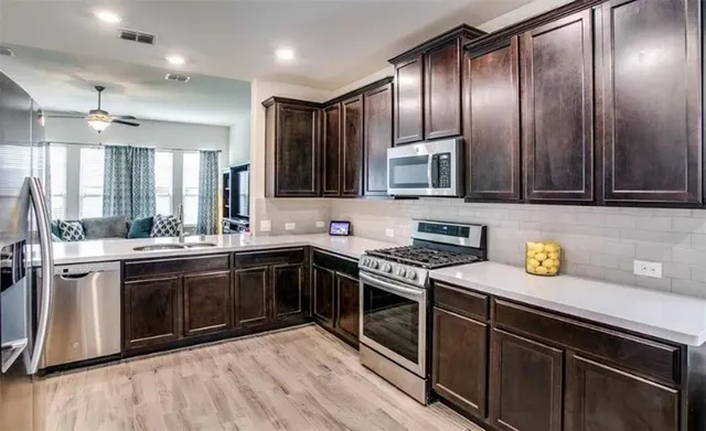a kitchen with stainless steel appliances granite countertop a stove a sink and a microwave