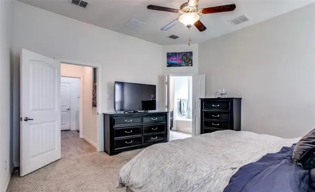 a bedroom with a bed and a flat tv screen on dresser