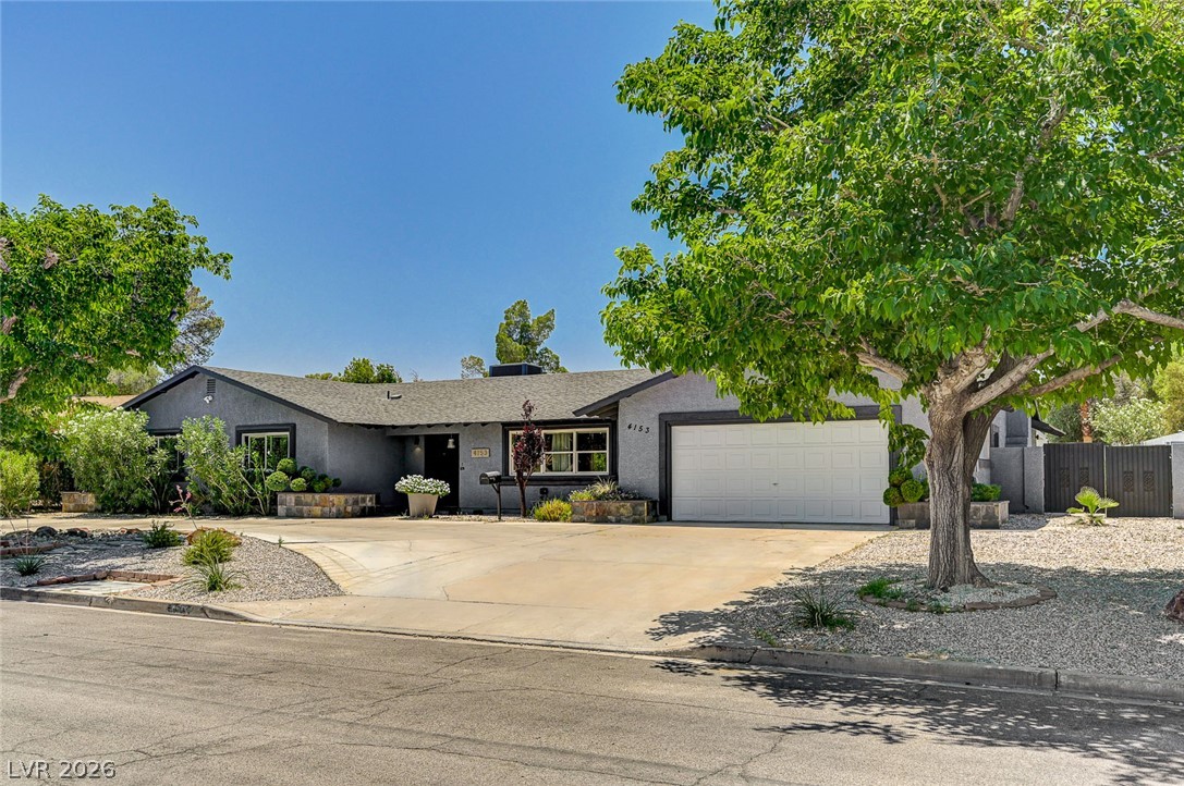 4153 Woodcrest Road Las Vegas, NV 89121 - Photo 2 of 58 A classic ranch-style home featuring a two-car garage and manicured desert landscaping.