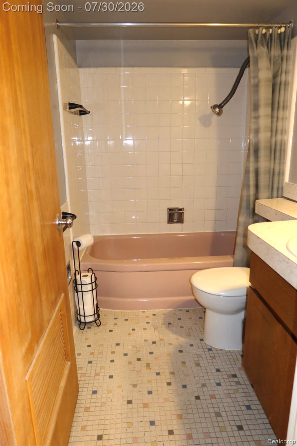 29232 Hoover Road, Unit 232 Warren, MI 48093 - Photo 6 of 22 Bathroom featuring a pink bathtub, white tiled shower surround, mosaic tile flooring, and a vanity with a surface-mounted sink