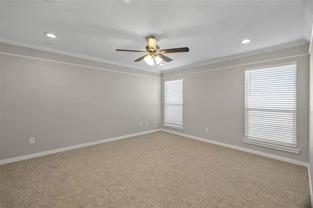 an empty room with windows and chandelier fan