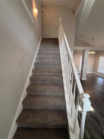 a view of an empty room and chandelier fan