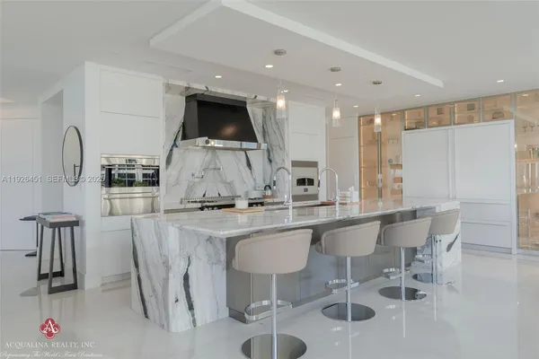 a large kitchen with stainless steel appliances a large counter top a stove and a refrigerator