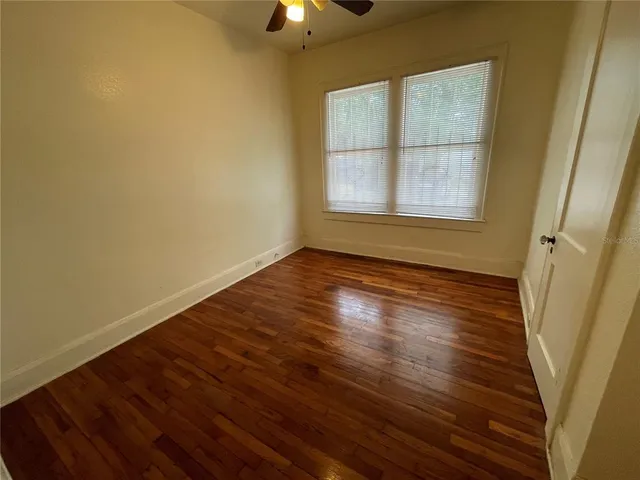 a view of an empty room with wooden floor and a window