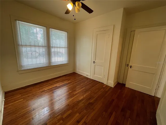 a view of an empty room with wooden floor and a window