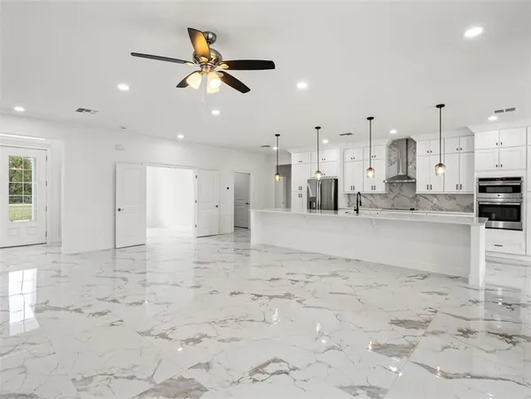 a view of a kitchen with kitchen island a counter top space appliances and cabinets