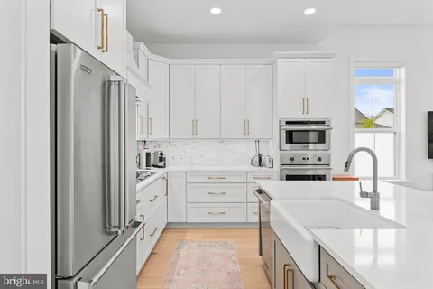 a kitchen with stainless steel appliances granite countertop a refrigerator sink and white cabinets