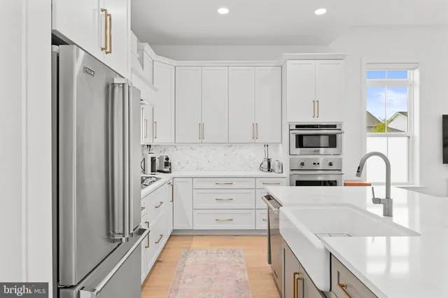 a kitchen with stainless steel appliances granite countertop a refrigerator sink and white cabinets