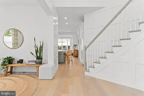 a living room with couches chairs and a large mirror with wooden floor