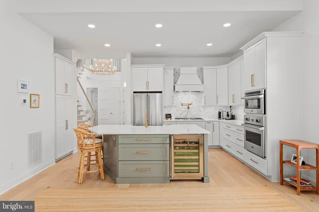 a kitchen with stainless steel appliances kitchen island granite countertop a stove a refrigerator and white cabinets with wooden floor