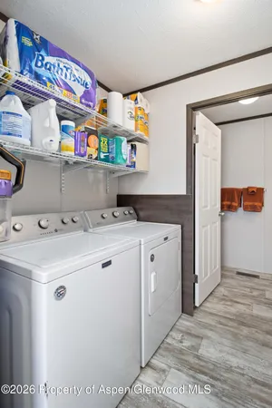 a utility room with stainless steel appliances granite countertop a sink and a refrigerator