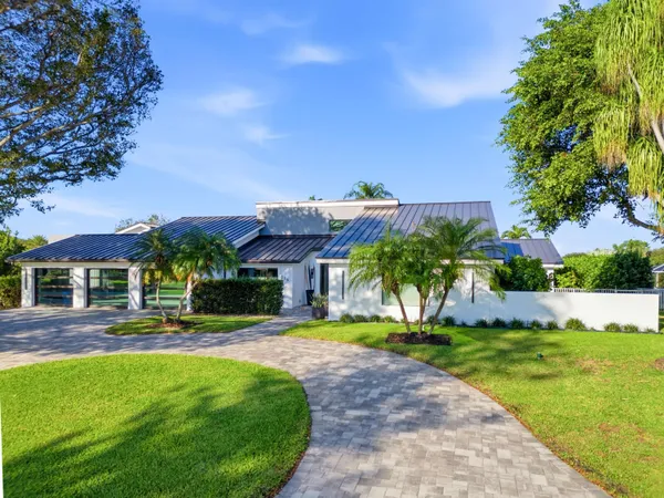 a front view of a house with a yard and palm trees