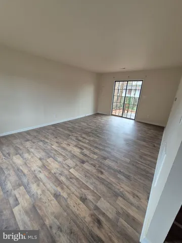 a view of an empty room with wooden floor and window