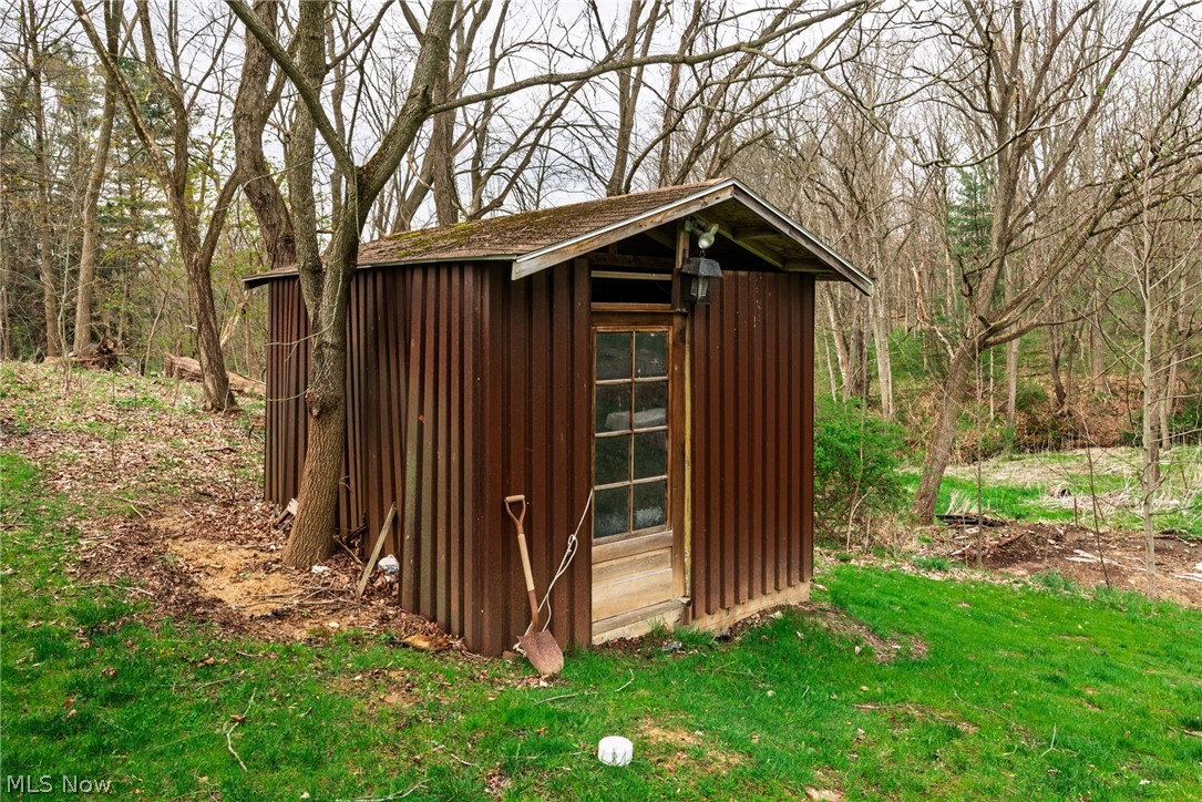 1069 West Nimisila Road New Franklin, OH 44216 - Photo 18 of 26 The property includes a rustic utility shed with a corrugated brown exterior and a windowed door, set on a grassy area surrounded by mature trees