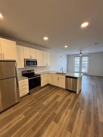 a large kitchen with cabinets wooden floor and stainless steel appliances