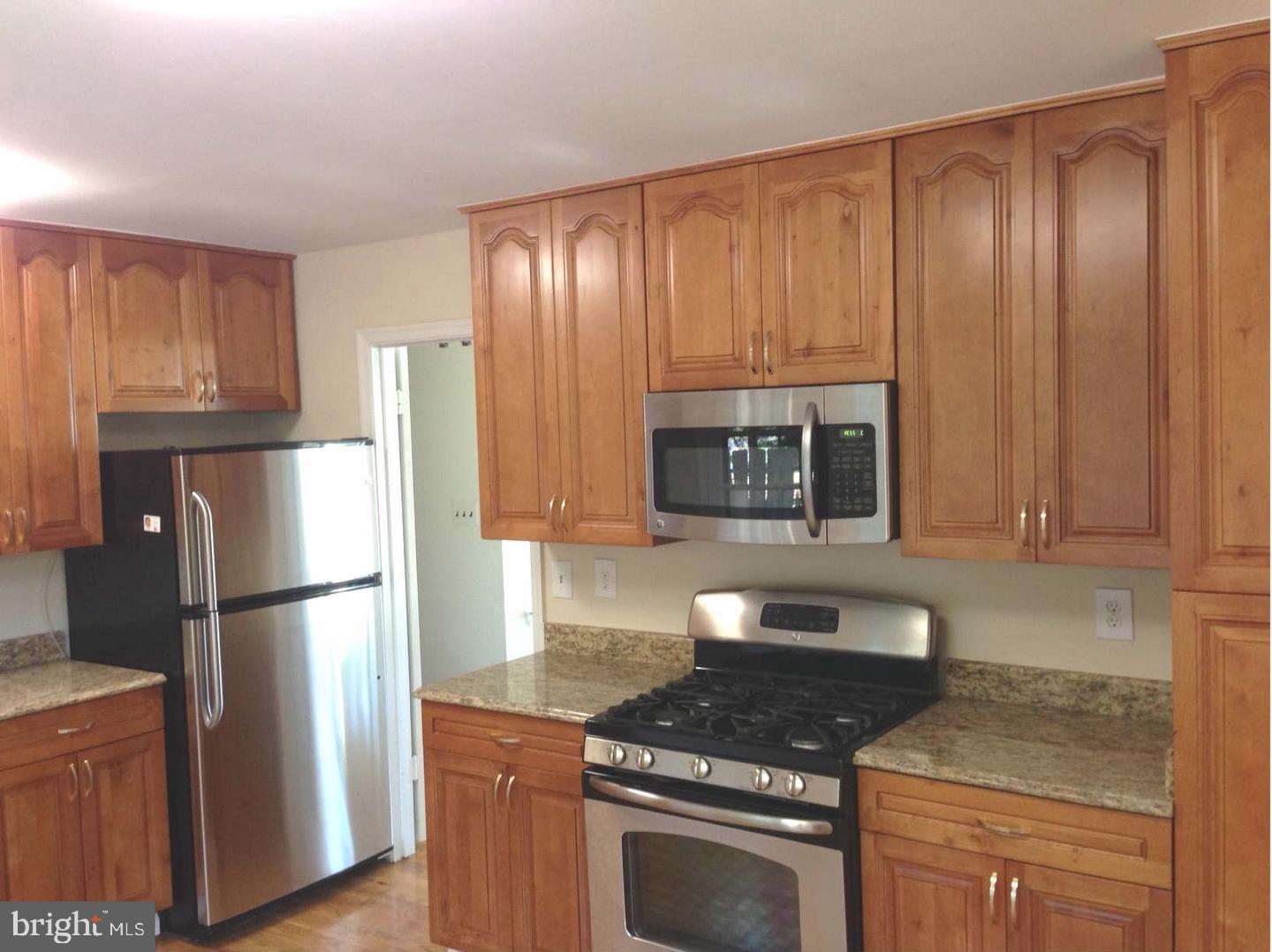 9700 Brookford Road Potomac, MD 20854 - Photo 2 of 27 a kitchen with granite countertop wooden cabinets and a refrigerator