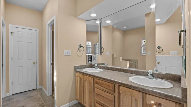 a bathroom with a granite countertop double vanity sink and a mirror