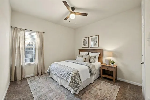 a bedroom with a bed painting on wall and a large window