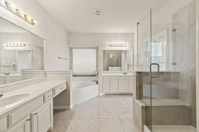 a large bathroom with a double vanity sink a toilet a mirror and shower