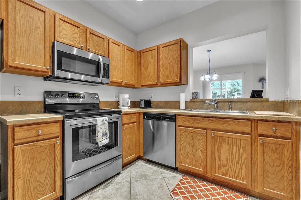 3954 Cherrybrook Loop Fort Myers, FL 33966 - Photo 18 of 47 a kitchen with stainless steel appliances granite countertop a stove a sink and a microwave