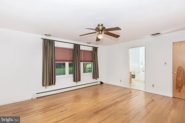a view of an empty room with a window and wooden floor