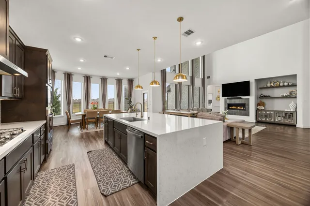 a large kitchen with stainless steel appliances a stove a sink dishwasher a dining table and chairs with wooden floor