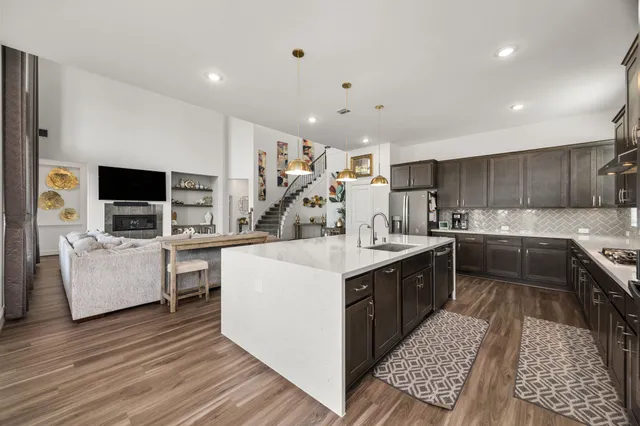 a large white kitchen with a stove top oven a sink dishwasher and a refrigerator with wooden floor