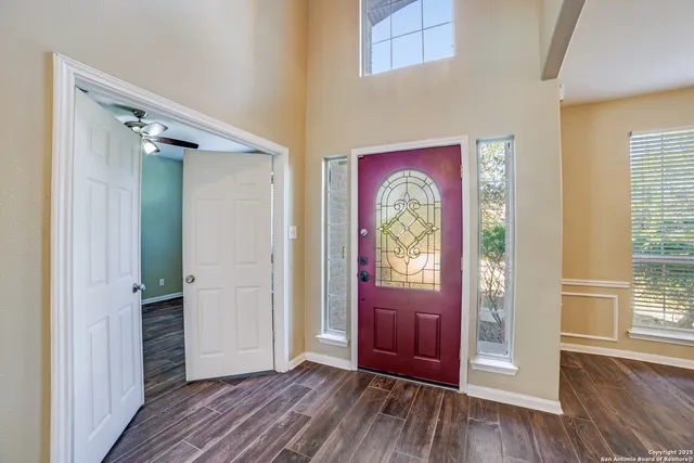 an entryway at a bedroom with wooden floor windows and front door