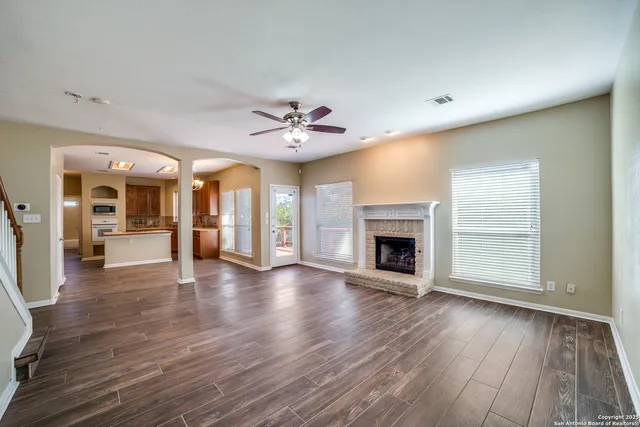 a view of an empty room with wooden floor and a fireplace