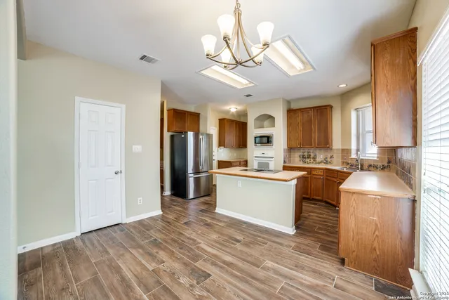 a kitchen with stainless steel appliances granite countertop a refrigerator a sink dishwasher a stove with wooden cabinets and floor