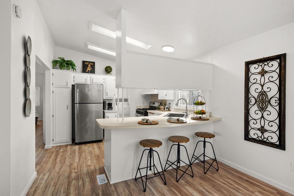 8620 Atlas View Drive Santee, CA 92071 - Photo 23 of 58 a kitchen with stainless steel appliances a refrigerator a stove a dining table and chairs with wooden floor