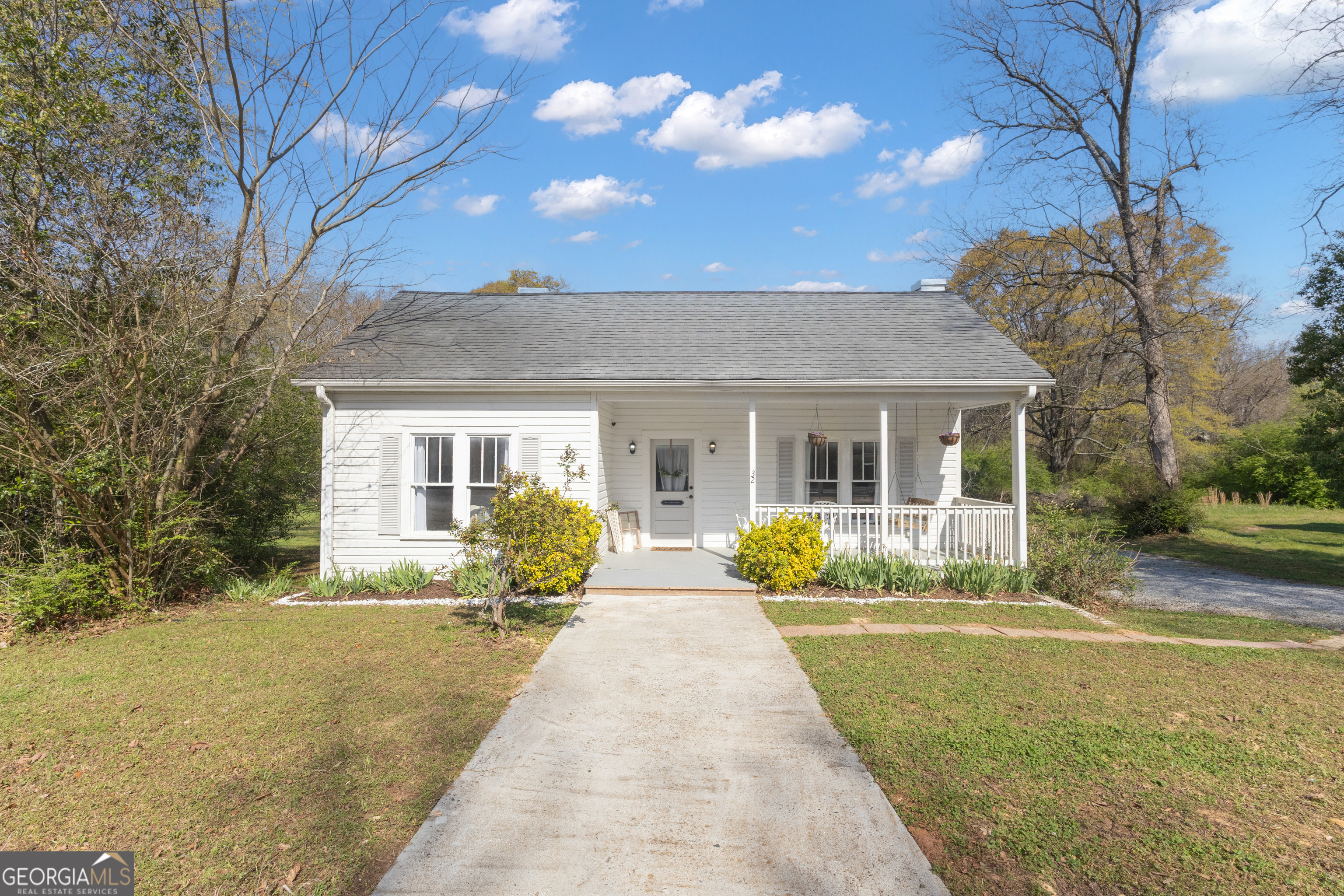 a view of house with yard chairs and large tree