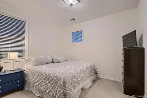 a bedroom with a bed and a flat tv screen on dresser