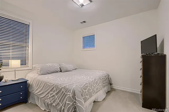 a bedroom with a bed and a flat tv screen on dresser