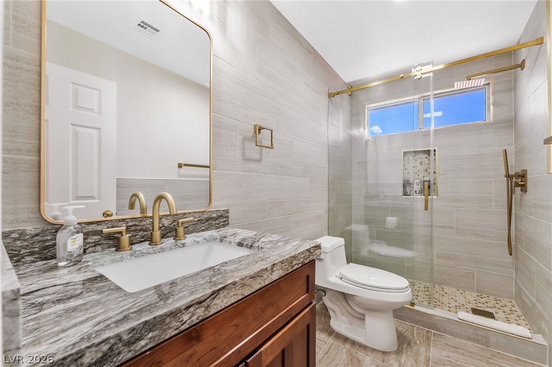 104 Appian Way Henderson, NV 89002 - Photo 20 of 24 Luxurious gold fixtures and sleek stone surfaces complete this modern bathroom's design.