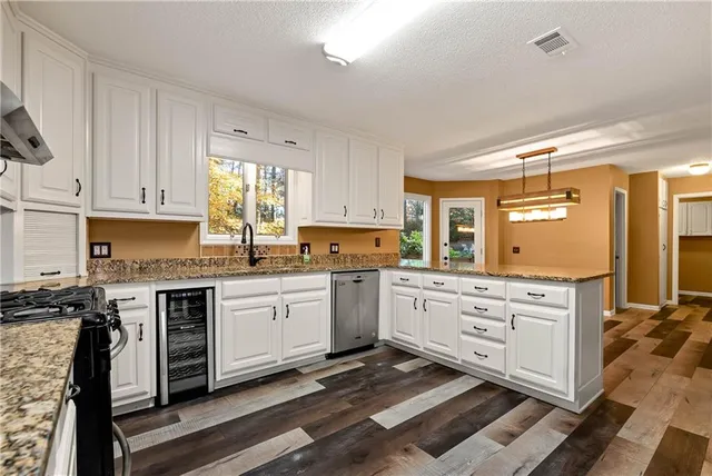 a kitchen with granite countertop white cabinets and stainless steel appliances