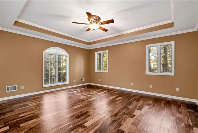 an empty room with windows and ceiling fan