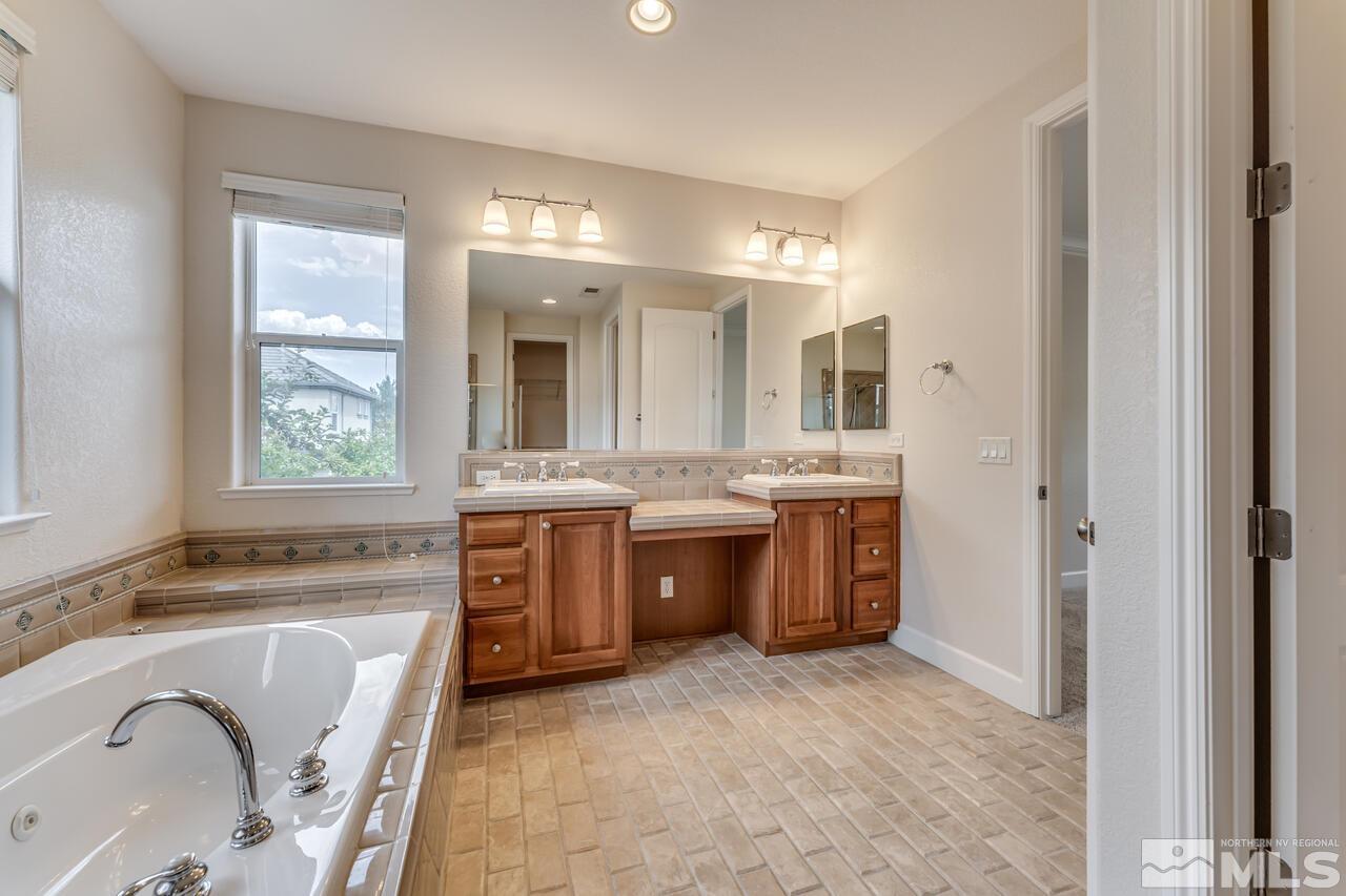 7625 Stone Bluff Way Reno, NV 89523 - Photo 21 of 32 a spacious bathroom with a granite countertop tub sink and mirror