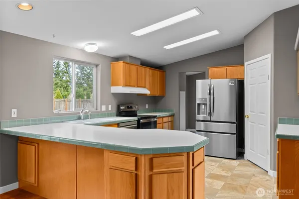 a kitchen with stainless steel appliances granite countertop a refrigerator a sink a stove and island