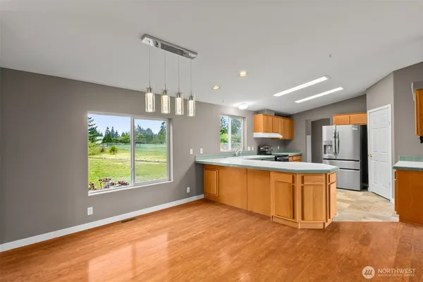 a large kitchen with stainless steel appliances granite countertop a refrigerator a sink dishwasher a stove and a large window