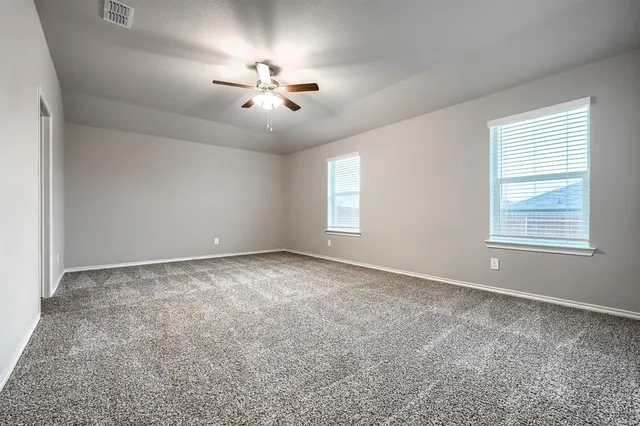 an empty room with windows and fan