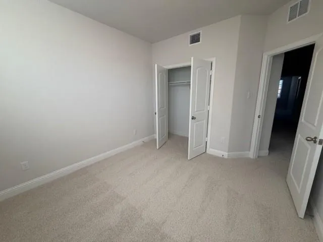 a view of an empty room with closet and a window