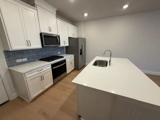 a kitchen with white cabinets sink and stainless steel appliances