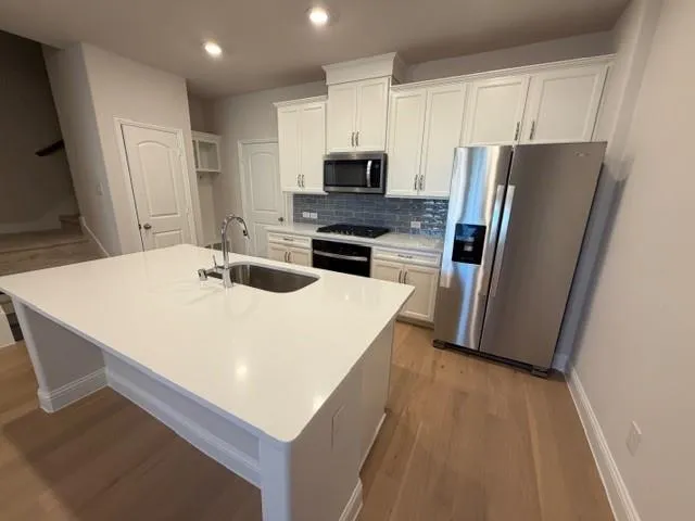 a kitchen with stainless steel appliances a microwave a sink a refrigerator a stove a microwave and island