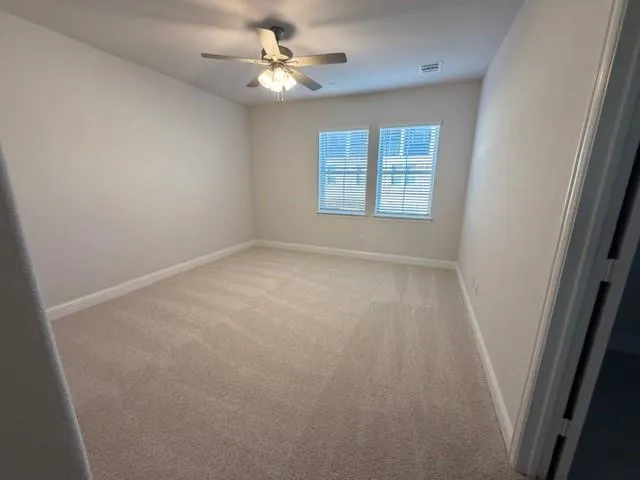 an empty room with windows and fan
