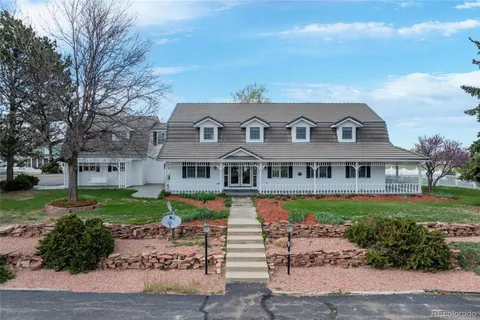 a front view of a house with garden and trees