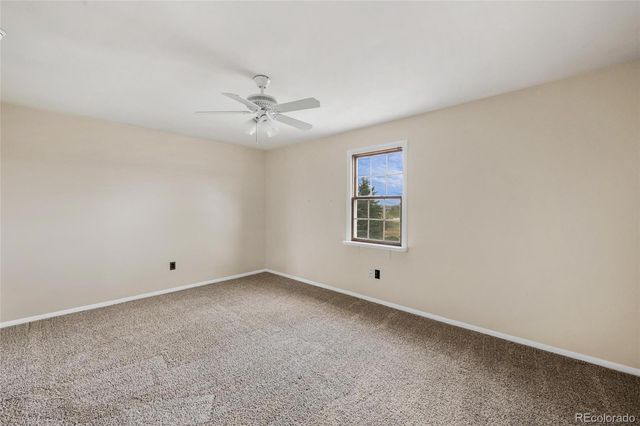 an empty room with a window and ceiling fan