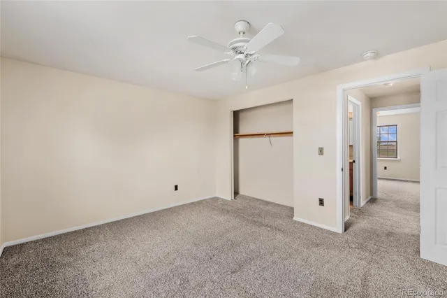 an empty room with a ceiling fan and a window
