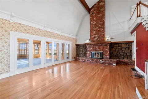a view of an empty room with wooden floor and a fireplace